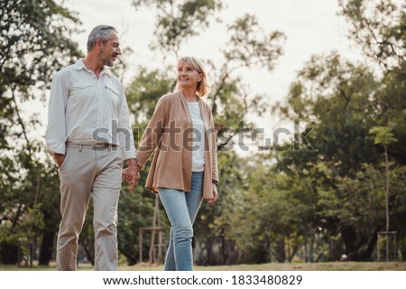 Romantic and elderly healthy lifestyle concept.Senior active caucasian couple holding hands looks happy in the park in the afternoon autumn sunlight,happy anniversary,happily retired with copy space. Royalty-Free Stock Photo #1833480829