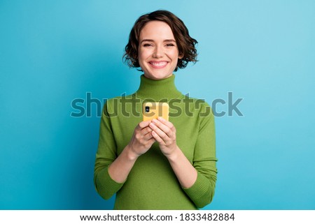 Portrait of positive cheerful girl use smartphone enjoy social network communication wear green style stylish trendy sweater isolated over blue color background