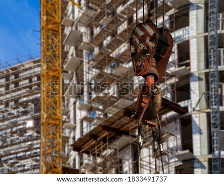 Construction crane hook with multi-storey building under construction with scaffolding (new residential complex) on the background, Moscow, Russia