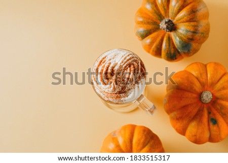 Spice pumpkin latte in glass with pumpkins on yellow background, copy space, top view