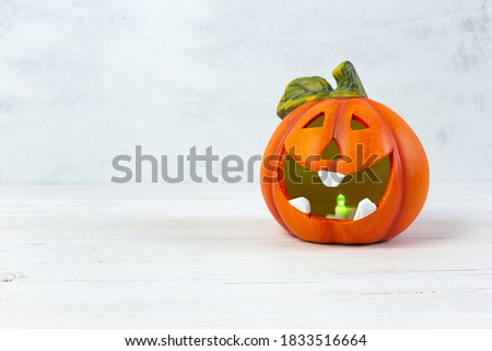 Orange decorative cheerful pumpkin lantern on a light background. Halloween, All Saints Day, a traditional fall holiday. Trick or treat. Jack lantern. Postcard. Copy space.