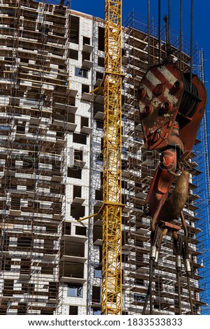 Construction crane hook with multi-storey building under construction with scaffolding (new residential complex) on the background, Moscow, Russia