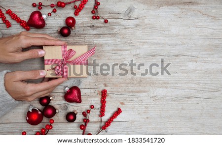 Christmas gift box on wooden background with red Christmas ornaments