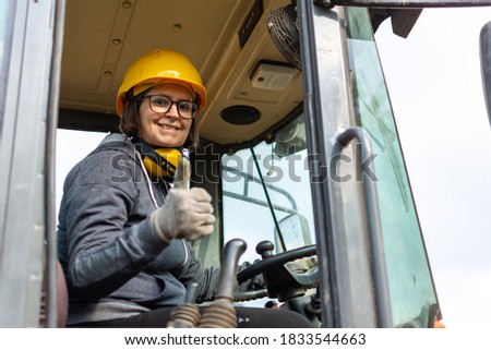 cheerful female excavator operator on construction site. Woman construction apprentice learning to drive heavy equipment Royalty-Free Stock Photo #1833544663