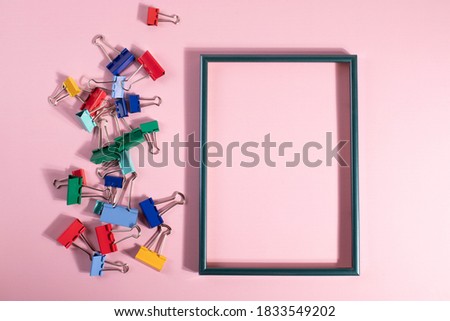 colourful metal paper clips and empty frame. minimalism style. 