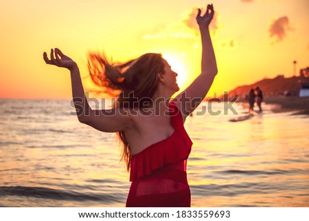carefree woman in red swimsuit dancing at sunset on the beach. mature woman relaxation vitality healthy lifestyle