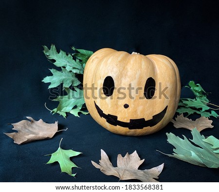 Isolated Halloween pumpkin head jack lantern with autumn leaves on black background