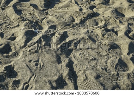 Footprints in the sand piled up on a pavement