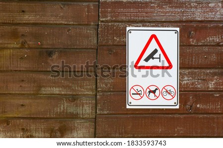 Prohibitory signs on a wooden fence. No smoking, dogs, bicycles. Video surveillance warning.