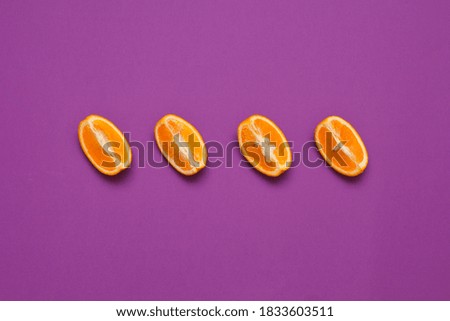 Four orange slices face the same direction against a purple background.