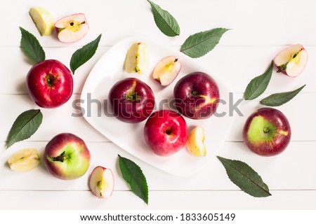 Apple slices, apples, green leaves on a white background top view. background with apples in a white plate on a white table.