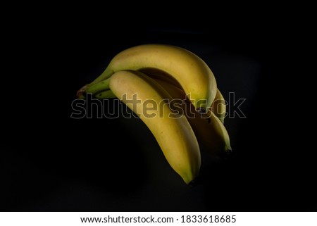 Beautiful ripe bananas on black background, healthy food concept, Light and shade photography
