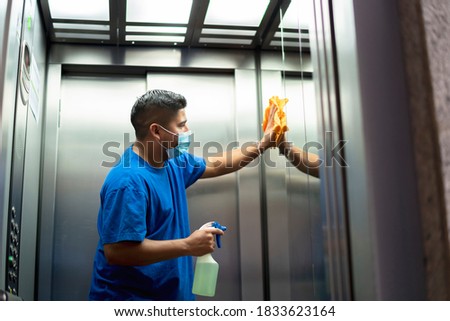 maintenance personnel disinfecting the interior of the elevator Royalty-Free Stock Photo #1833623164