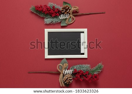 Christmas composition, small chalk board, frame of spruce and red berries with copy space on dark red background. Blank for postcard layout. Festive, New Year concept. Horizontal, flat lay.