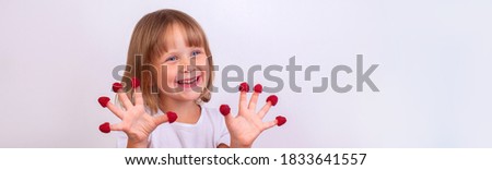 Narrow photo of a cheerful little girl with raspberries. 