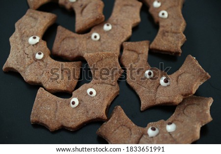 Chocolate Halloween sweets cookies handmade and baked in bat shaped with textile cobweb on the background. 