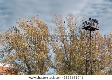 Metallic observation tower in industrial zone. Yellow autumn trees on background. Selective focus.