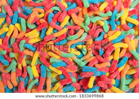 Sour candy worms close up background. Covered in granulated sugar. Flat lay top view from above.