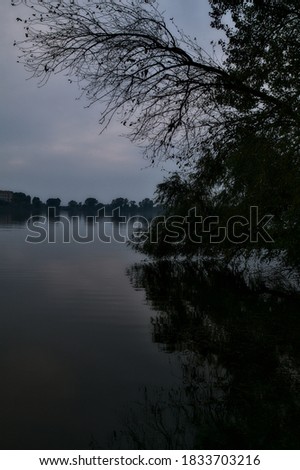 Lake at sunset in autumn framed by a tree with its reflection casted in the water