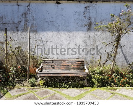 beautiful aged wooden rustic bench with concrete floor and cracked concrete vintage wall texture background 