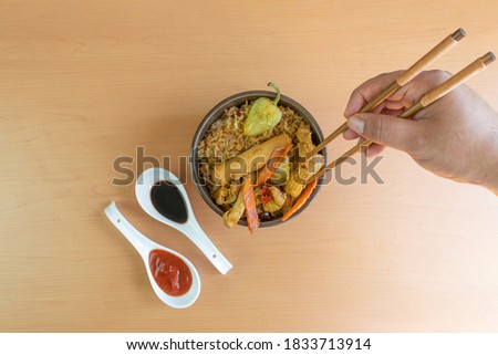 gourmet chinese food with chopsticks. in bowl with fried rice, chicken, vegetables, chun kun, soy sauce and siracha sauce Royalty-Free Stock Photo #1833713914