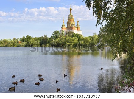 Kolonistsky Park in Peterhof. Cathedral of saints Peter and Paul in the Russian architectural style of the XIX century on the Bank of Olga pond, ducks on the water Royalty-Free Stock Photo #1833718939