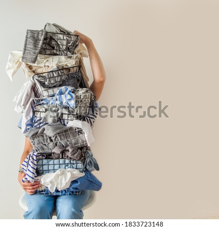 Surprised woman holding metal laundry basket with messy clothes on white background. Laundry. Isolated housewife. Copy space. Textile. Dirty wardrobe. Decluttering concept. Disorganized wife. Royalty-Free Stock Photo #1833723148