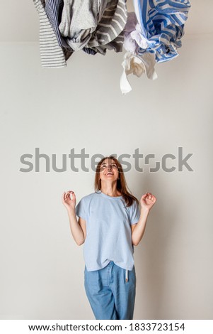 Caucasian housewife holding heap of dirty clothing. Laundry. Chaos concept. Background. Busy woman.