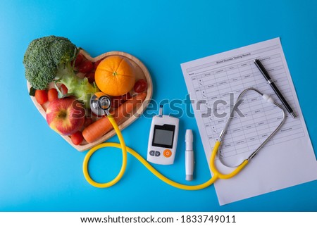 World diabetes day. National American diabetic awareness. Free Glucose Monitors on blue background. Yellow stethoscope check fruit on heart plate. Healthcare and medical concept Royalty-Free Stock Photo #1833749011