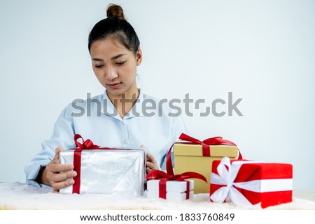 Woman in a blue shirt holding a white gift box tied with a red ribbon present for the festival of giving special holidays like Christmas, Valentine's Day.