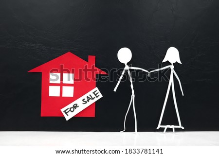 Couple human stick figure looking at a red house with for sale signage in black background with copy space. Buying home for newlywed concept.