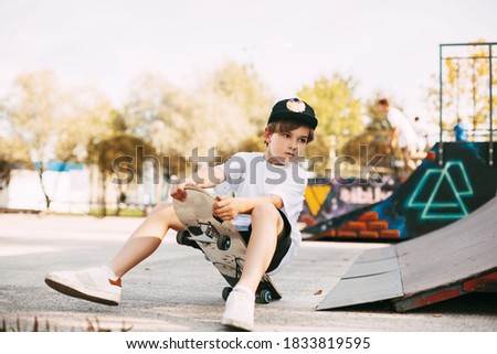 A boy performs tricks on a skateboard in a special area in the Park. A boy falls off a skate while riding in a skatepark. The child is having fun. Active rest in the fresh air