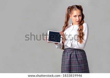 A beautiful schoolgirl poses with a tablet in her hands.