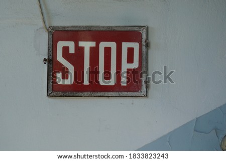 Vintage rectangular red metal stop sign on a blue and white wall