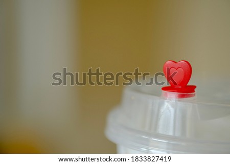 Small plastic heart Placed on the lid of a coffee cup And there is an area to put text beside the picture