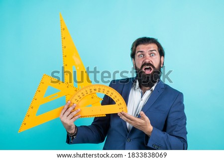 shocked mature teacher holding triangle and protractor tool. bearded man engineer work with ruler. prepare for geometry exam. architecht or lecturer on math lesson. back to school. measure and size.