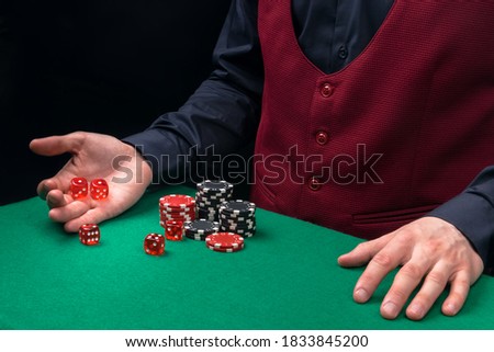 the dealer's hands roll the dice on the green cloth of the poker table