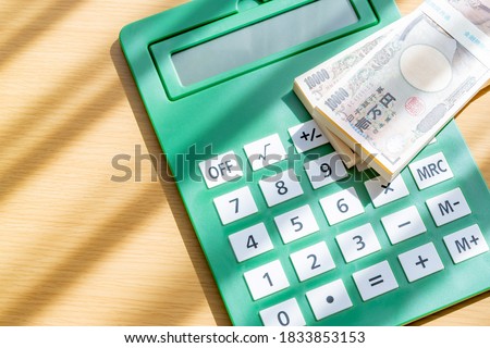 A very large calculator and a wad of 10,000 yen bills.
Translation on bill's text: "Bank of Japan Tickets" "One hundred thousand yen" "The Bank of Japan".