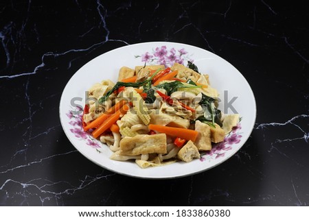 Fried and stirred spicy dried tofu with carrot, basil and chilly on the plate. Famous vegetarian menu in Chinese restaurant. High fiber and low fat menu. Royalty-Free Stock Photo #1833860380