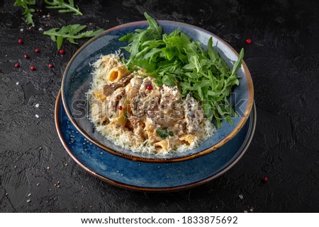 Gourmet delicious penne pasta cooked with beef and cheese with arugula salad. Balanced nutritious dish. Still life for restaurant poster