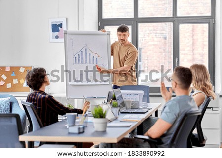business, people and corporate concept - team of startuppers with statistics on flip chart working at office