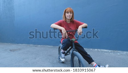 Young woman posing with BMX bicycle outdoor on the street 