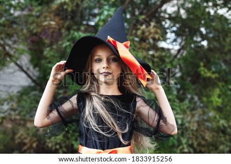 Little girl in witch costume outdoor. Happy Halloween
