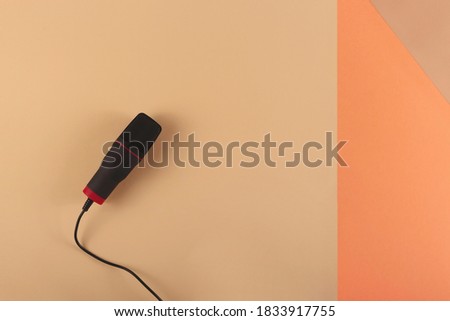 Podcasting concept - microphone at blogger's workplace on a combined beige background.