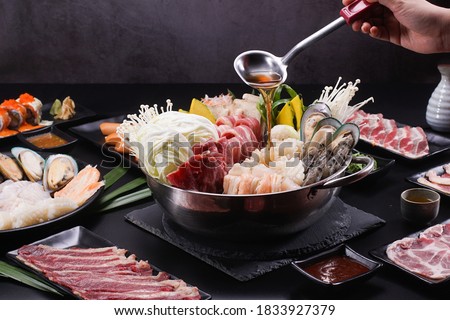 Shabu Shabu or Sukiyaki, a popular dish of pork, beef, shrimp, squid, seafood and fresh vegetables. Placed on a table with a boiling pot boiling in a Japanese restaurant. Royalty-Free Stock Photo #1833927379