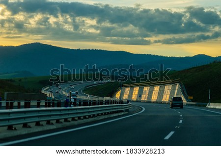 Motorway surrounded by mountains in the background of the colorful sunset