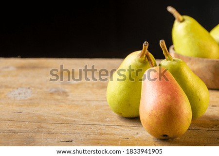 Top view of ercolinas pears grouped on wooden table and black background horizontally with copy space