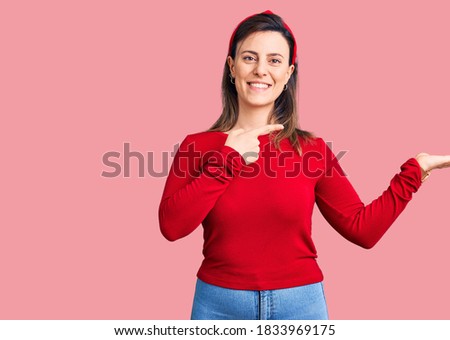 Young beautiful woman wearing casual clothes amazed and smiling to the camera while presenting with hand and pointing with finger. 