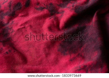 Red textile crumpled rag with dark traces of engine oil and gasoline