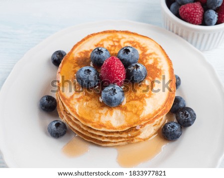 Stack of pancakes with fresh blueberries served in a dish with maple syrup. Delicious breakfast